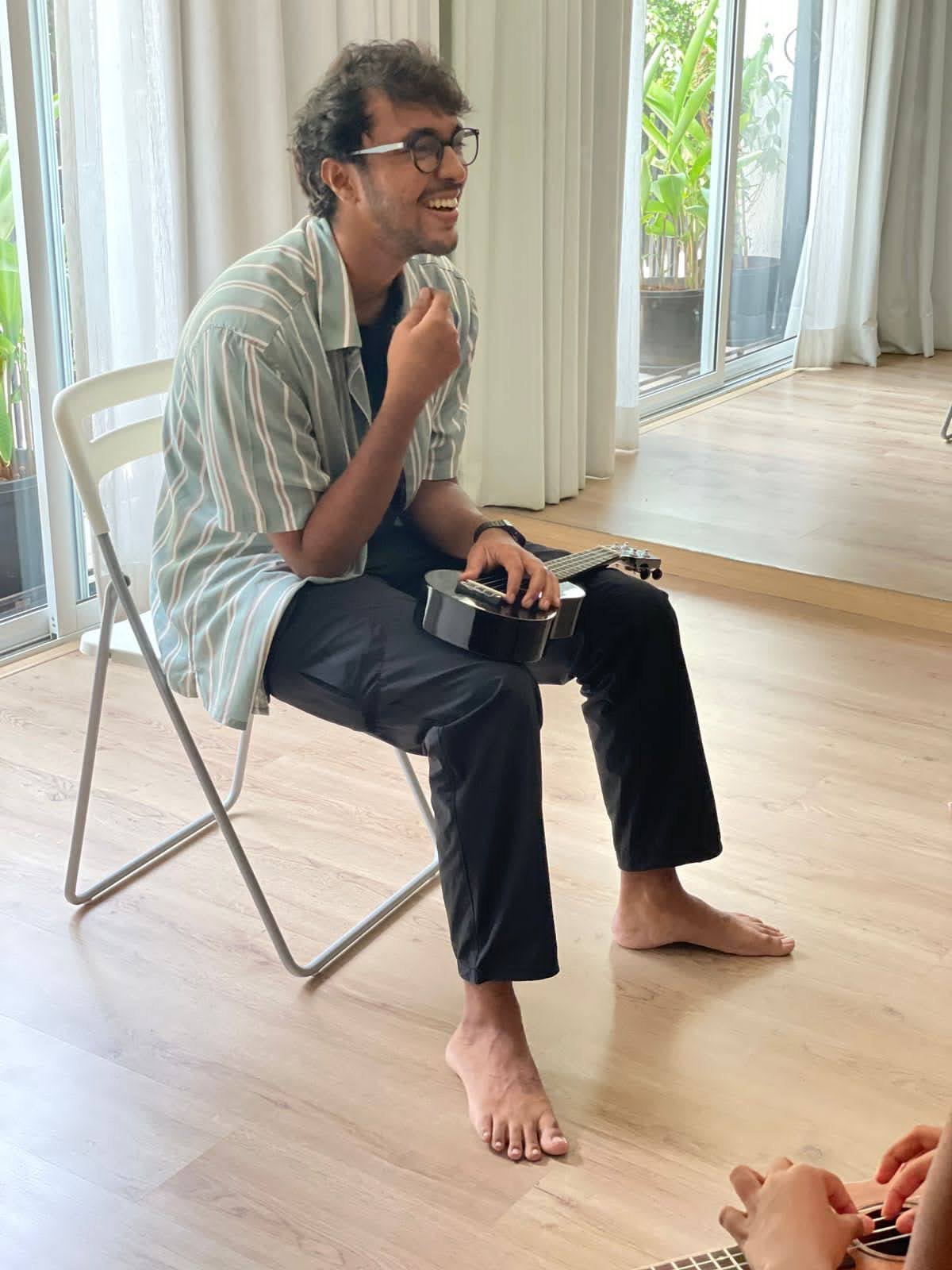 Akshit Deshmukh laughing with a ukulele during a Long Play session, a student playing beside him